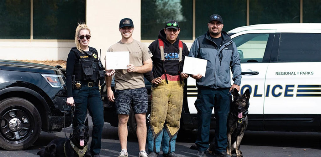 Dog and handlers beside police vehicles